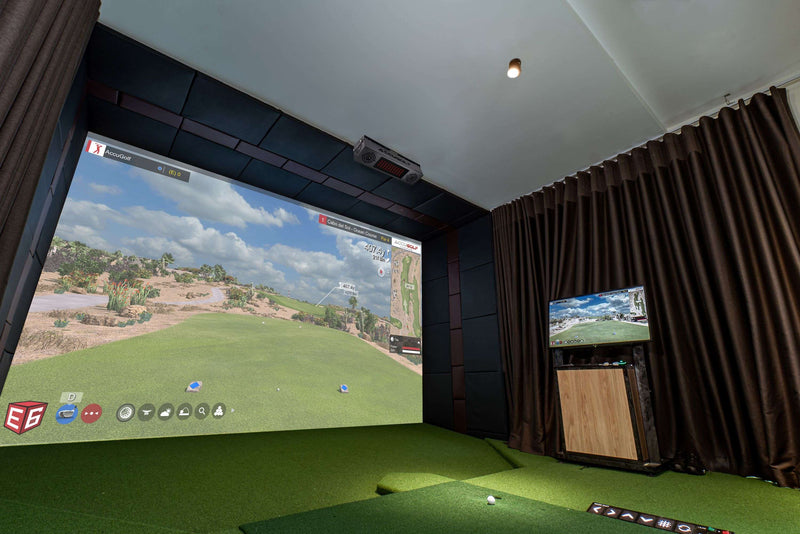 Indoor golf simulator setup with large screen and additional monitor.
